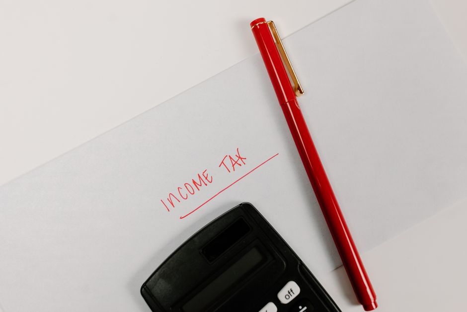 Kalkulator i crvena olovka na papiru s natpisom 'Income Tax', simbol financijskog planiranja