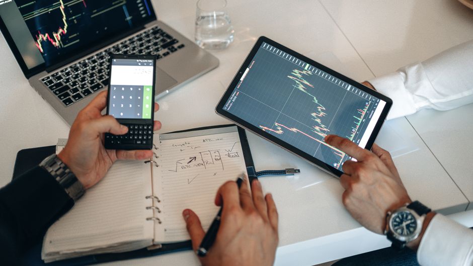 Financijski stručnjaci analiziraju grafikone na digitalnim uređajima tijekom sastanka